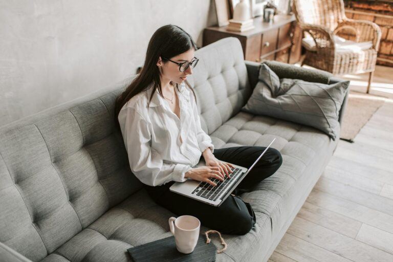 a woman sitting on a couch using a laptop